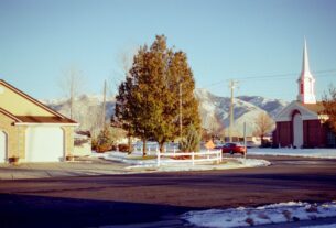 Clean suburban street splits into two paths on a bright sunny day, symbolizing the choice homeowners face with real estate...