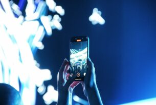 Traveler in a modern airport holds a smartphone displaying a glowing, futuristic interface, symbolizing the seamless integ...